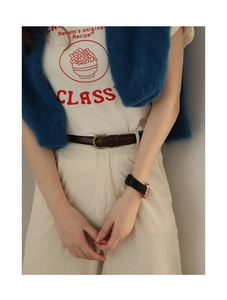 Detail eines schmalen dunkelbraunen Ledergürtels mit Vintage-Schnalle an cremefarbener Hose