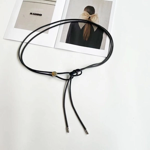 Gros plan détaillé d'une ceinture fine en cuir noir avec une boucle en disque argenté