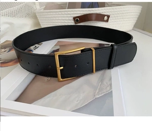 Close-up of black leather belt with golden square buckle and natural grain texture