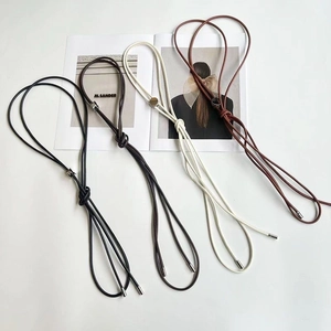 Détail des fines ceintures en cuir nouées en noir marron blanc et couleur beige
