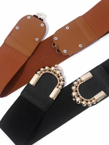 Détail de larges ceintures élastiques avec cuir marron et boucle dorée à perles