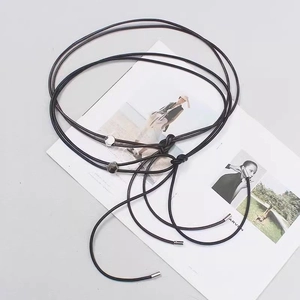 Détail d'une fine corde de taille en cuir noir avec embouts métalliques et perles