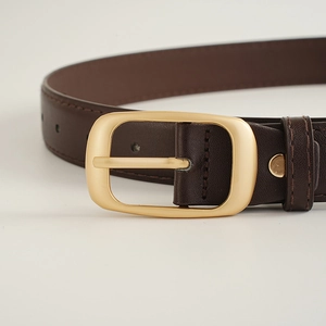Détail d'une ceinture en similicuir marron foncé avec boucle ardillon dorée mate et couture