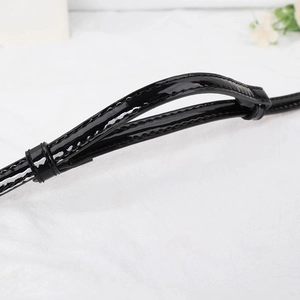 Détail d'une ceinture en cuir verni noir brillant avec coutures nettes et passant