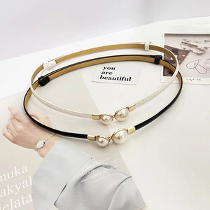 Detail of elegant patent leather skinny belts with gold-tone pearl buckle for women
