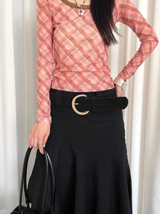 Detail of vintage suede wide belt with large gold buckle on a black asymmetric skirt