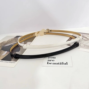 Detail of slim black and white patent leather belts with circular gold buckles