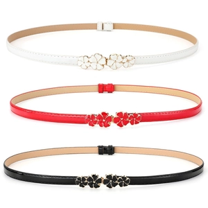 Detail of floral metal buckles on thin waist belts in white, red and black finishes