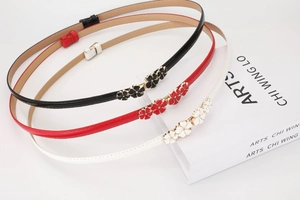 Detailed view of glossy skinny belts featuring vintage floral metal buckles in three colors