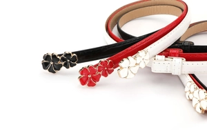 Detail of red black and white skinny belts with golden double flower buckle design