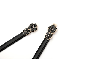 Detail of thin black patent leather belt with golden metal floral enamel buckle