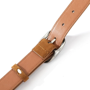 Detail of vintage silver pin buckle and brown suede loop on a retro leather belt