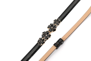 Detail of elegant black faux suede belt featuring golden framed floral metal buckles