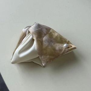 Detail of satin floral print hair claw featuring a white pearl and gold metal logo tag