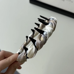 Close-up of pleated satin headband with faux pearl accents and champagne gradient finish