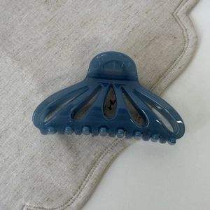 Detail view of a navy blue fan-shaped hollow hair claw on beige linen fabric