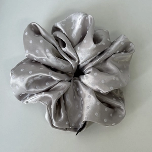 Detailed view of silver grey satin scrunchie with white polka dots and soft texture