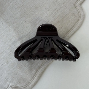 Macro shot of high-gloss scallop-shaped hair claw clip with smooth polished finish