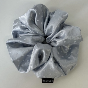 Detail showing light blue polka dot satin scrunchie with soft silk texture and fashion label