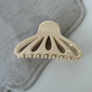Detailed view of large beige fan-shaped cutout hair claw clip on linen background