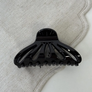 Detail of glossy black scalloped cutout hair claw clip with a polished finish