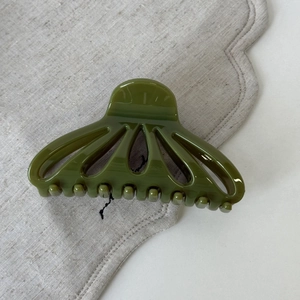 Detail view of olive green hollow fan-shaped hair claw clip with smooth glossy finish