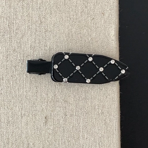 Detail of elegant black quilted hair clip with sparkling rhinestones and lattice stitching