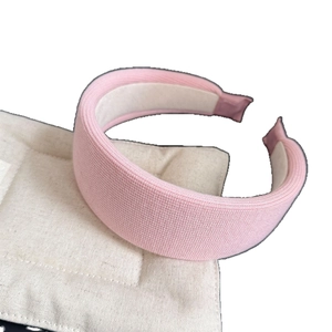 Pink chunky knitted wide headband on a soft beige quilted surface for women