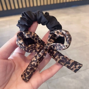 Dettaglio dell'elastico per capelli con fiocco leopardato in tessuto nero plissettato