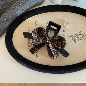 Dettaglio del fermaglio per capelli con fiocco leopardato e pinza nera per capelli folti