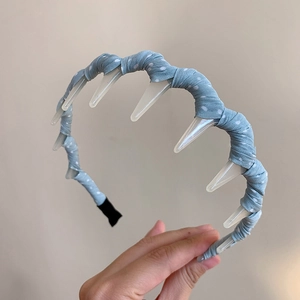 Close-up of light blue polka dot headband with integrated transparent hair clips for styling