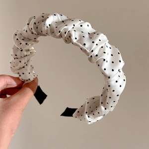 Détail du serre-tête plissé à pois en tissu satiné avec des volants souples