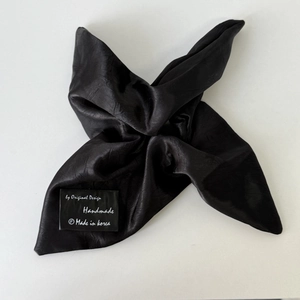 Detailed macro of a black satin hair scrunchie with a handmade in Korea brand label
