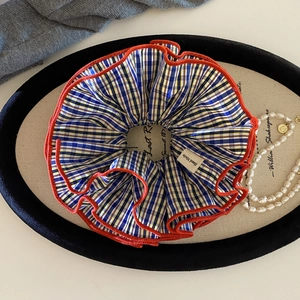 Plaid scrunchie with orange trim and Hand Made label on a stylish accessory display