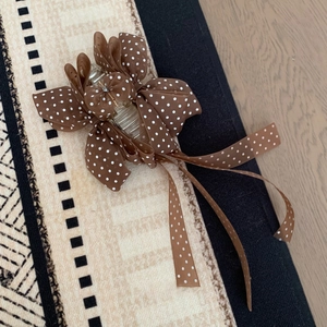 Détail de la pince à cheveux avec nœud en ruban marron à pois et texture en tissu