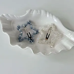 Detail shot of crystal star hair clips in grey-blue and white on a shell tray