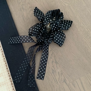 Détail d'une pince à cheveux à pois noirs avec d'élégants longs rubans fluides