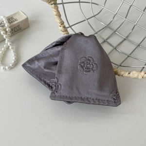 Macro view of luxurious purple silk eye mask featuring embossed camellia flower patterns