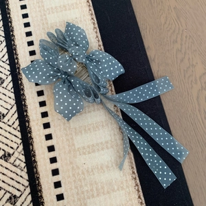 Vue détaillée d'une pince à cheveux à pois bleu poudré avec de longs rubans élégants
