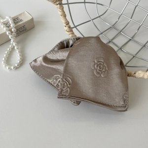 Detail of champagne gold satin hair claw with embossed rose embroidery and silky texture