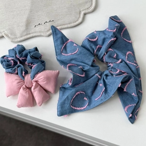 Détail d'un chouchou en denim bleu avec broderie cœur rose et bords effilochés