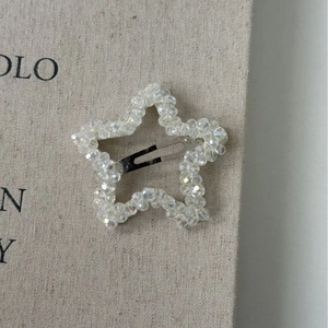 Macro detail of star-shaped crystal BB clip with intricate beaded texture on linen