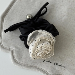 Close-up of black fabric hair scrunchie with polka dot tulle rose and silver bead detail