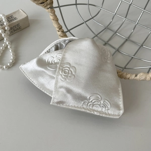 Detail of cream silk hair clip with rose embossing and elegant satin texture finish
