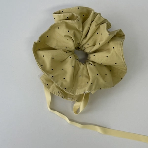 Gros plan détaillé d'un chouchou jaune à pois avec rubans et texture en coton doux