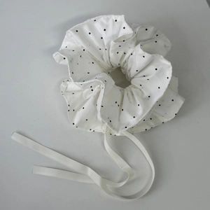 Gros plan d'un chouchou blanc à pois avec de longs rubans décoratifs de style coréen
