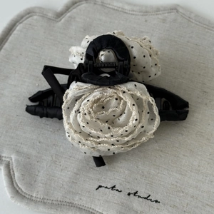 Detailed view of layered polka dot mesh roses on a sleek black hair claw clip