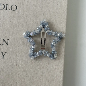 Detailed macro view of a light blue star-shaped crystal beaded hair clip on fabric