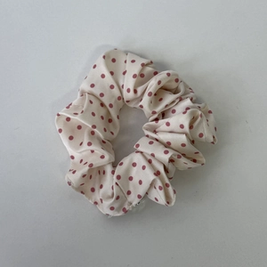 Detailansicht von cremefarbenem Seiden-Scrunchie mit roten Punkten und Faltenstruktur