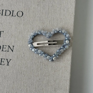 Macro shot of ice blue heart-shaped hair clip with faux crystal beads on metal base